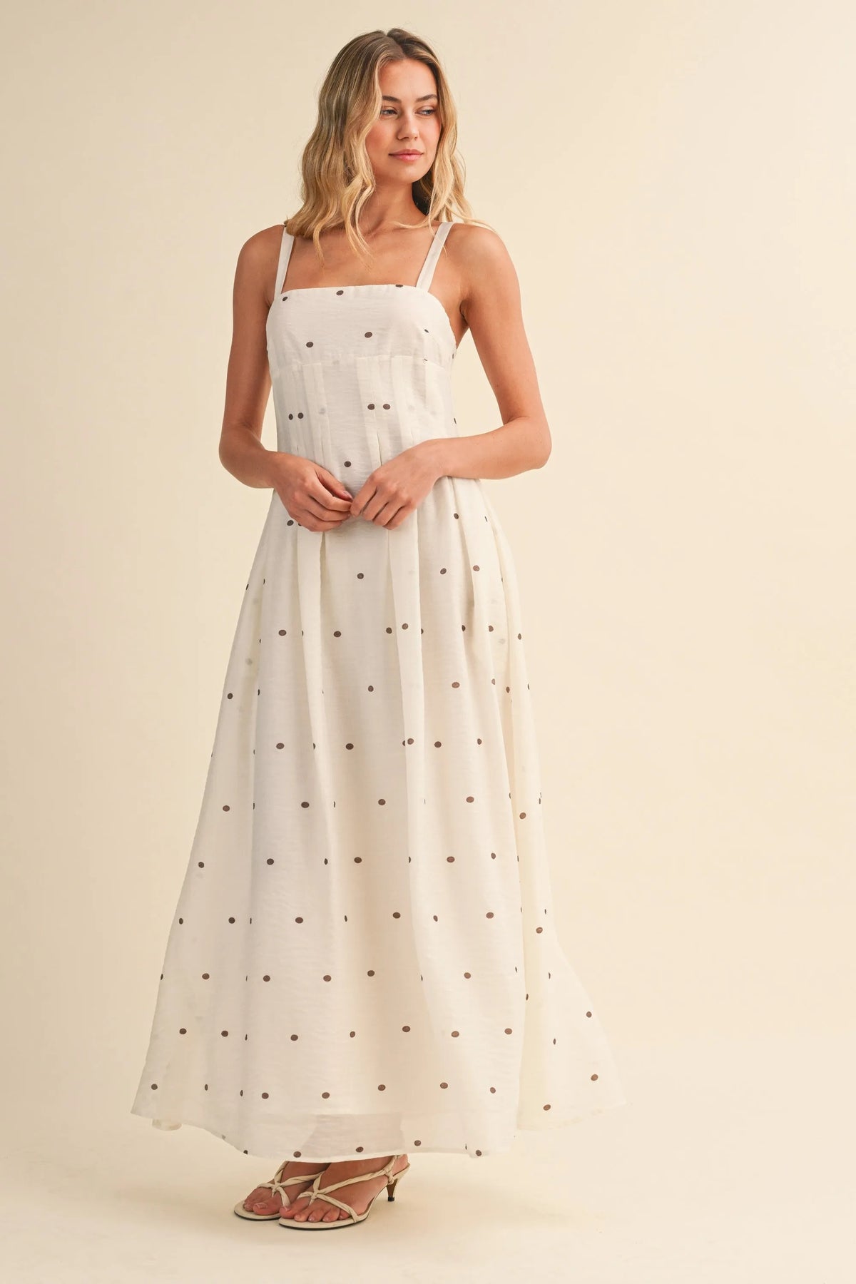 A flowing white polka dot maxi dress with pin tuck detailing and thin spaghetti straps perfect for summer wear