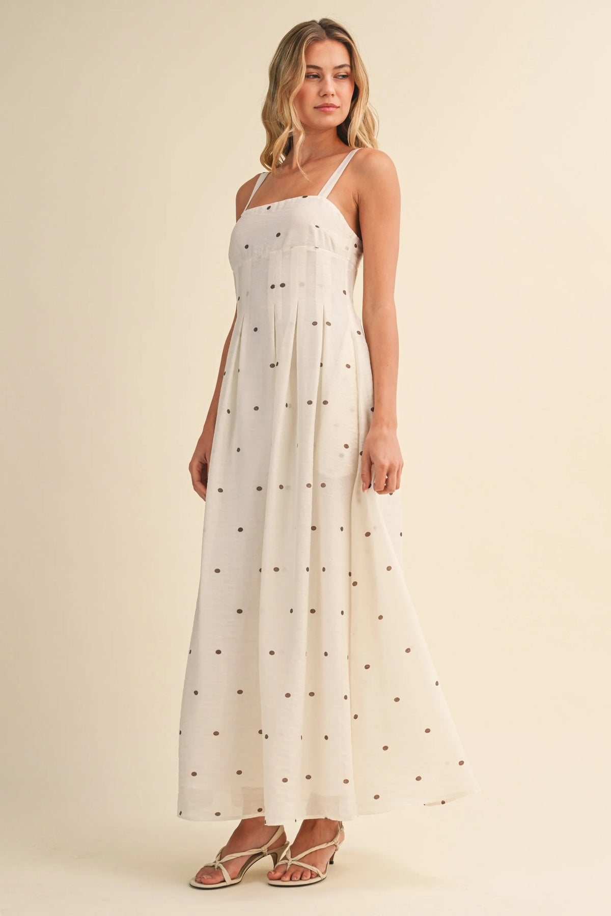 A flowing white maxi dress with delicate black polka dot print and pin tuck detailing with thin spaghetti straps