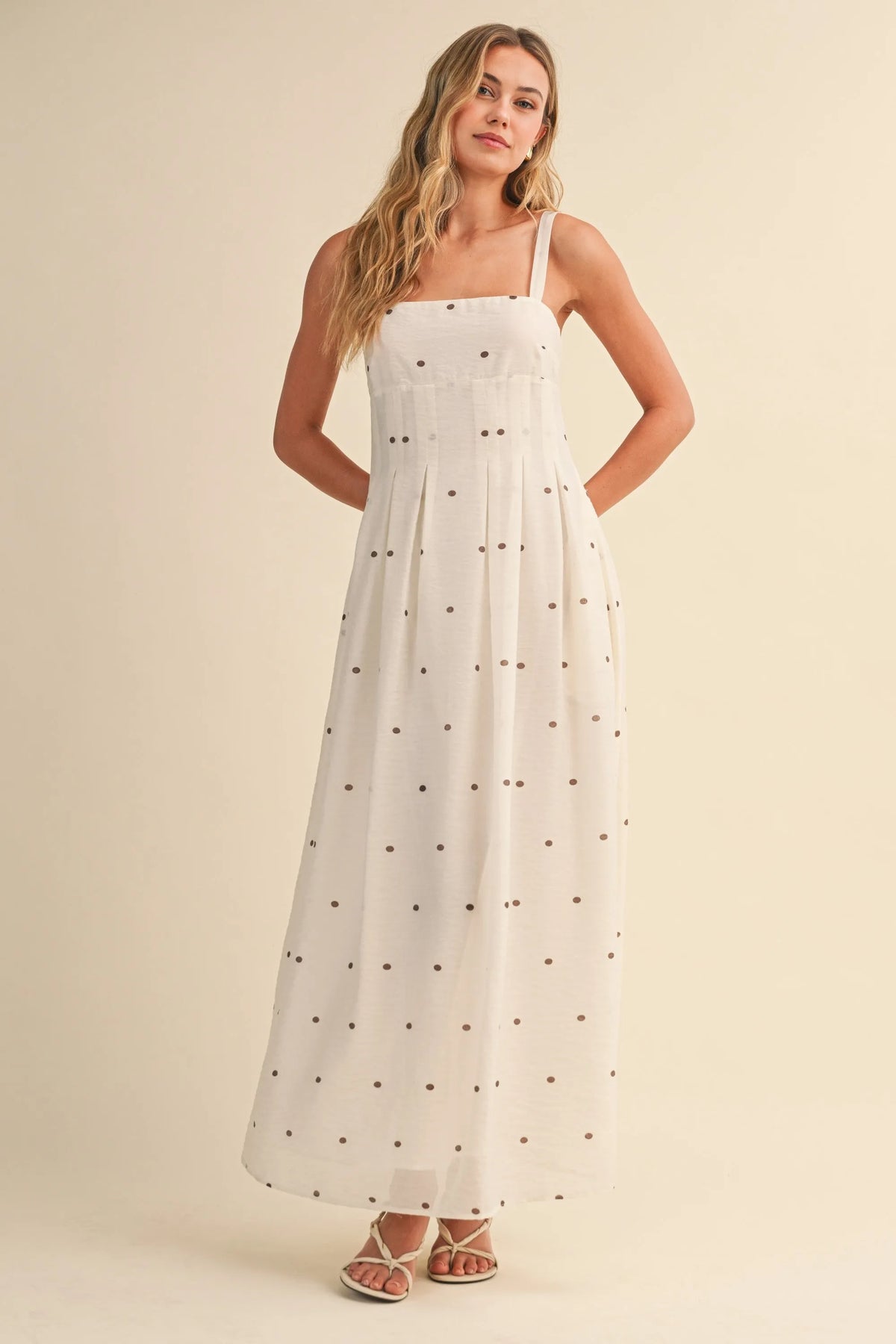 A flowing white polka dot pin tuck maxi dress with delicate black dots and thin spaghetti straps