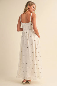 A flowing white maxi dress with delicate black polka dot print and pin tuck detailing with thin spaghetti straps