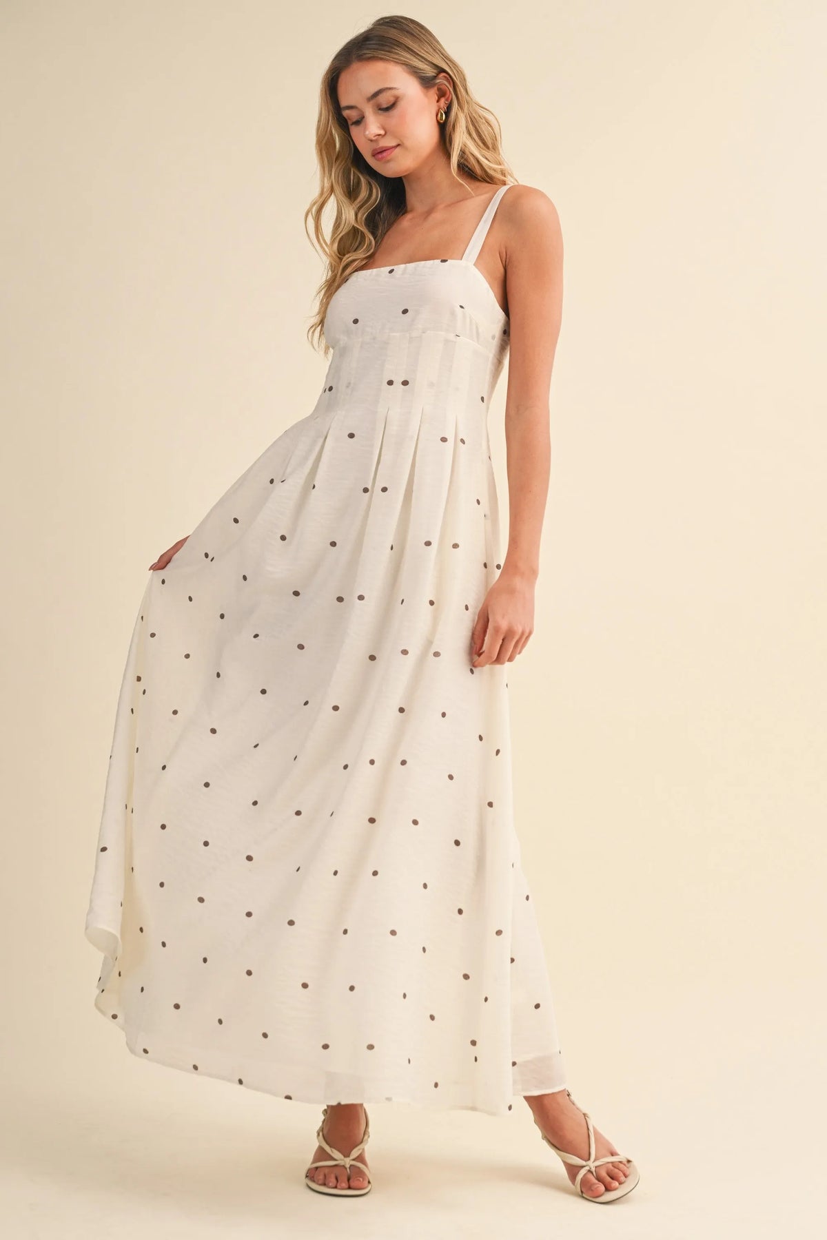 A flowing white maxi dress with delicate black polka dots and pin tuck detailing with thin spaghetti straps