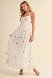 A flowing white maxi dress with delicate black polka dots and pin tuck detailing with thin spaghetti straps