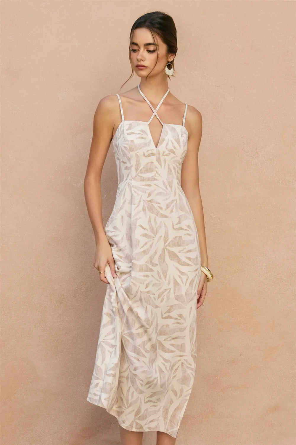 A flowing white sleeveless maxi dress with tropical leaf pattern and delicate leaf v cut spaghetti straps