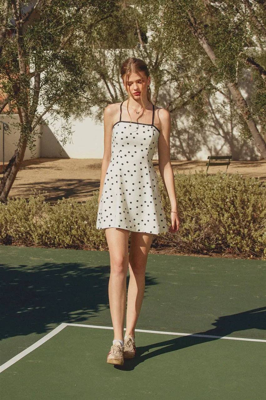 White mini dress with black polka dot pattern and contrast bind thin straps in the back view