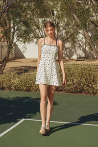 White mini dress with black polka dot pattern and contrast bind thin straps in the back view