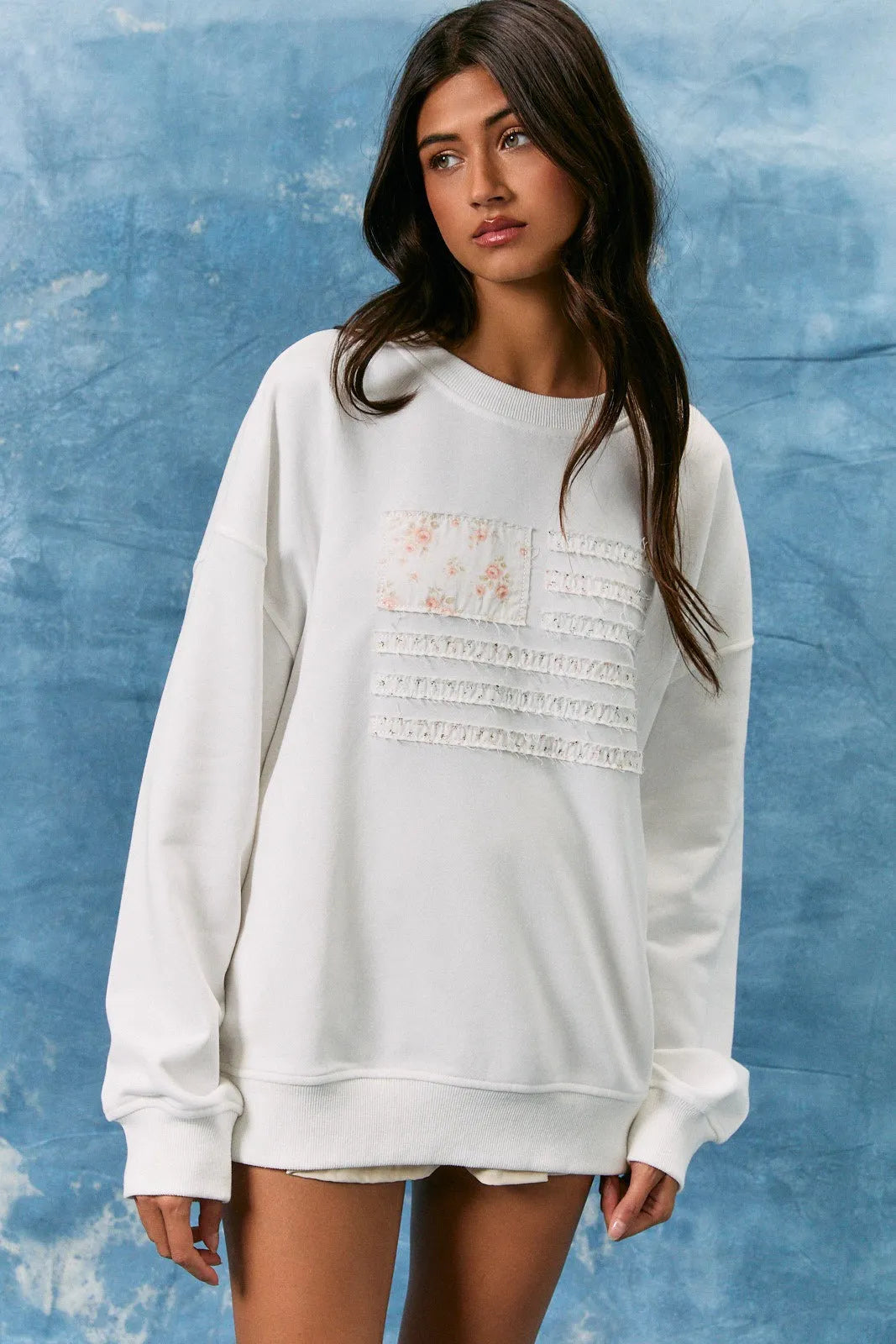 White oversized long sleeve crew neck sweatshirt with floral lace appliqué and usa flag design on front