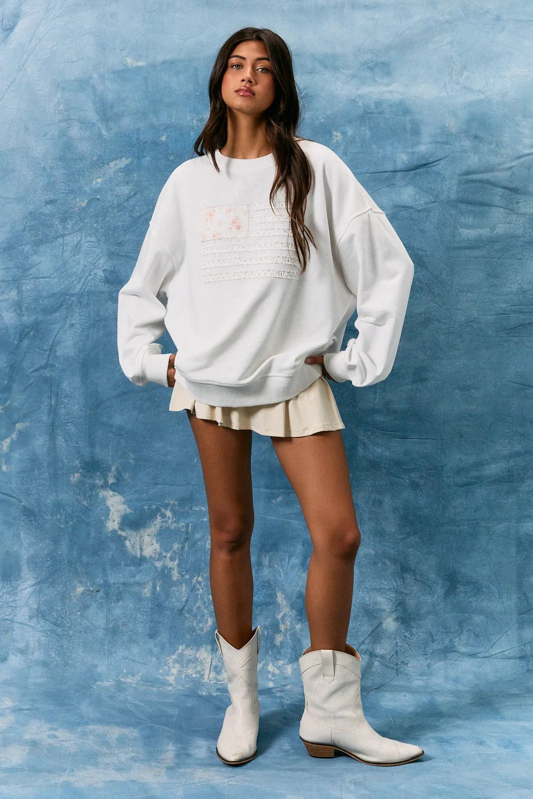 White oversized long sleeve crew neck sweatshirt with subtle embroidered usa flag graphic on the front