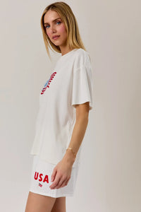 White oversized round neck t shirt with usa flag graphic embroidered in red and blue on the chest