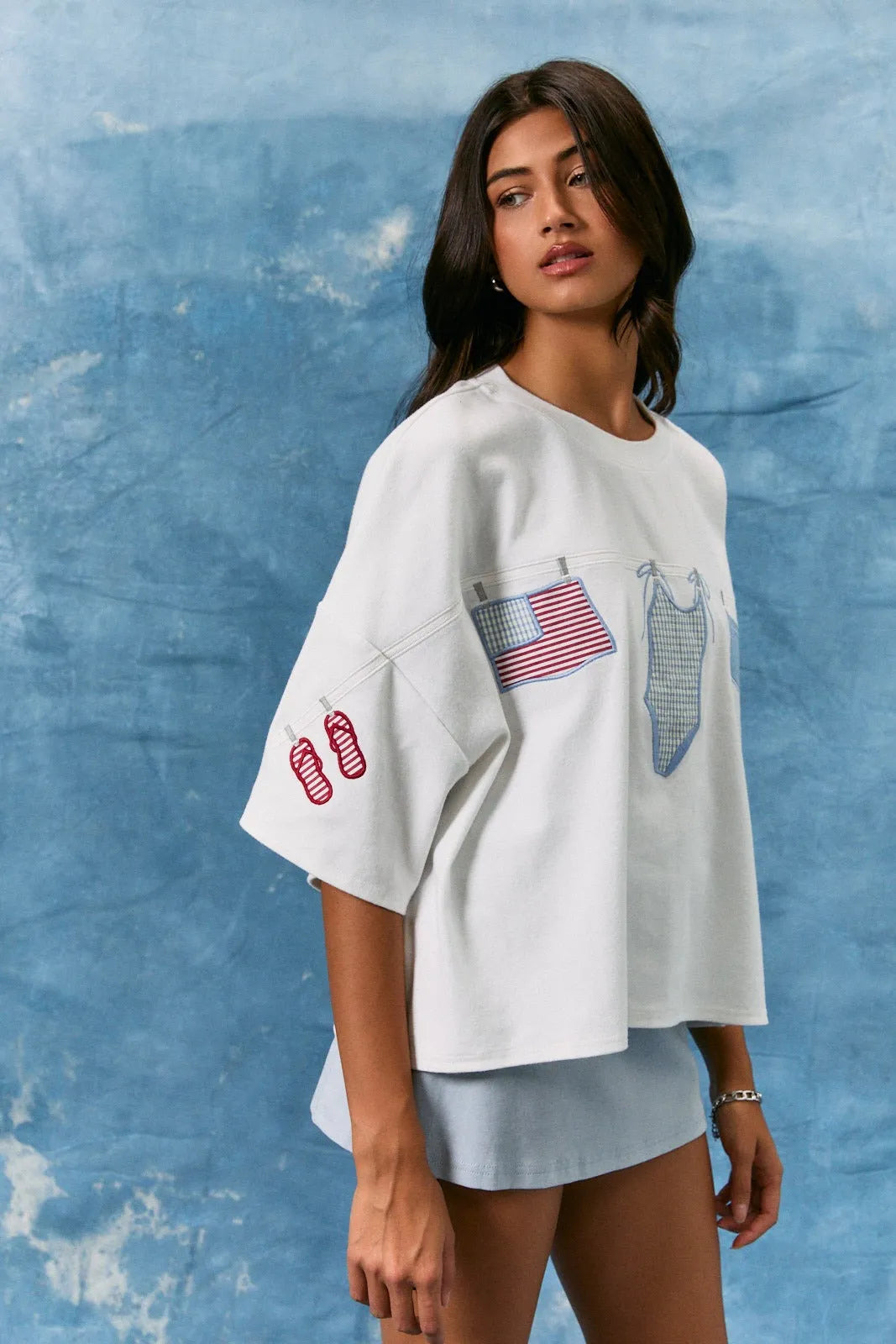 White oversized short sleeve americana graphic top with embroidered american flag swimsuit and flip-flops on sleeve and front