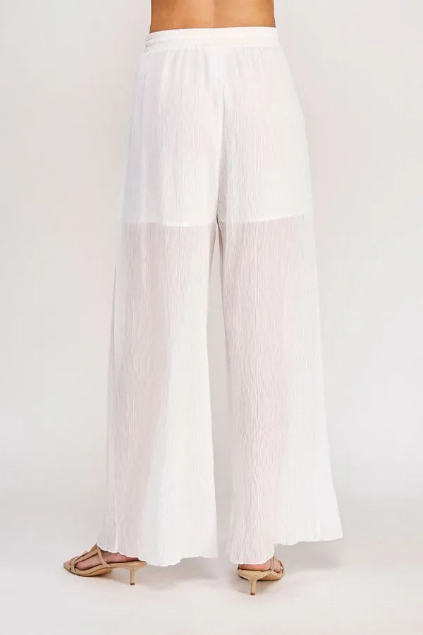 White pleated wide-leg textured woven pants with a sheer overlay and an elastic tie waist for adjustable fit