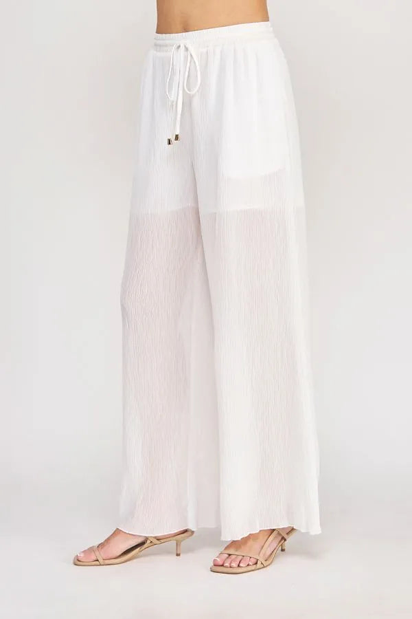 White pleated wide-leg pants with an elastic tie waist featuring textured woven fabric and a drawstring waistband