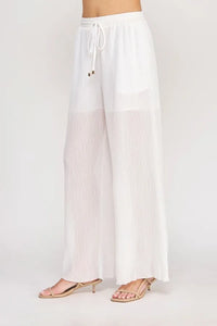 White pleated wide-leg pants with an elastic tie waist featuring textured woven fabric and a drawstring waistband