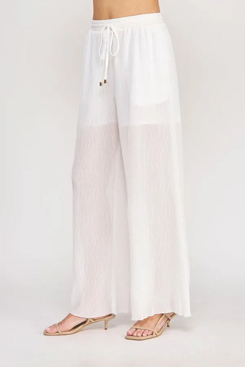 White pleated wide-leg pants with an elastic tie waist featuring textured woven fabric and a drawstring waistband