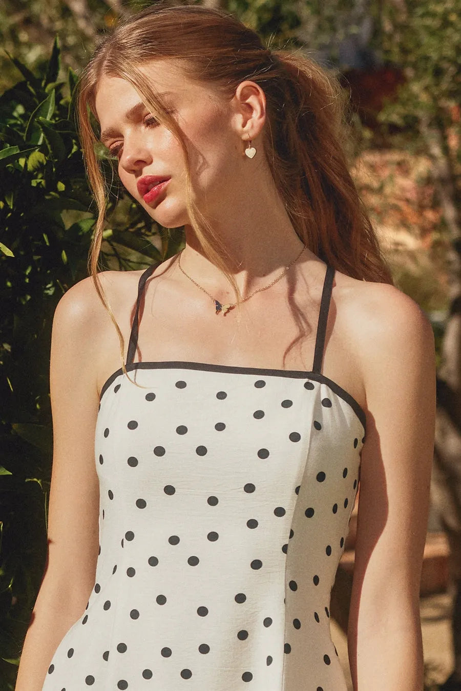 A white polka dot contrast bind mini dress with black straps and a fitted silhouette