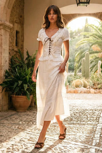 A white lace-trimmed midi dress with a corset-style bodice paired with a boho breeze tiered maxi skirt