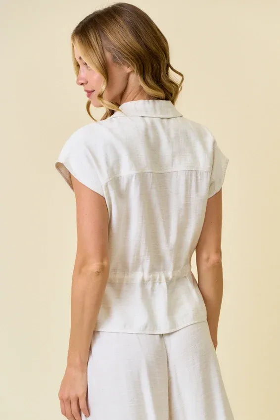 A white linen vest blouse with front zip closure drawstring waist short sleeves and a collar