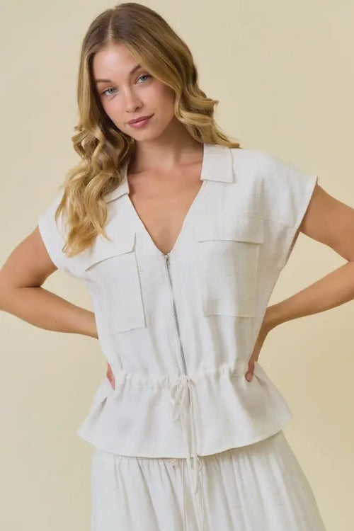 White linen vest blouse with drawstring waist and zip closure featuring collar and two chest pockets