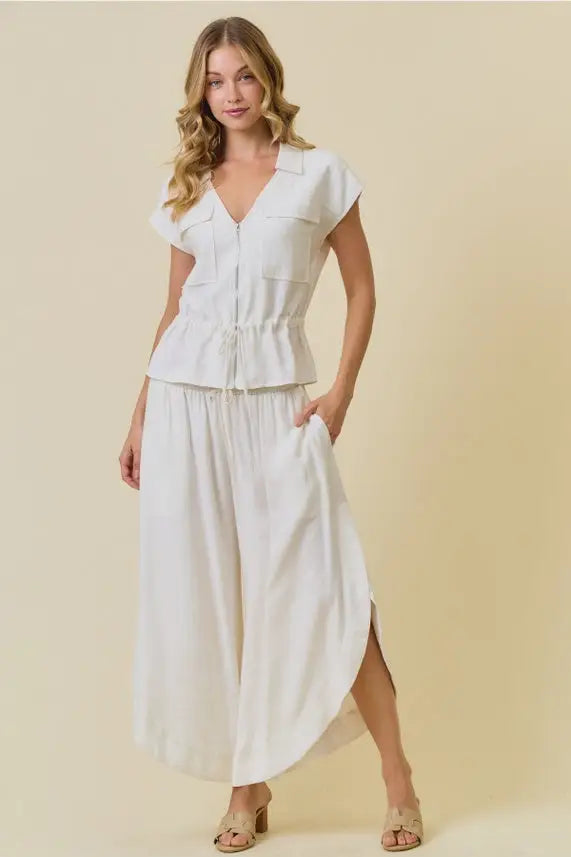 White short-sleeved peplum top with front zipper and chest pockets paired with rounded hem split sides pants from shop daisy women’s boho chic clothing