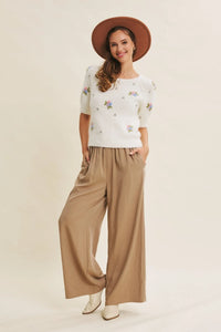 White short-sleeved sweater with pastel floral embroidery paired with wide leg step washed pants