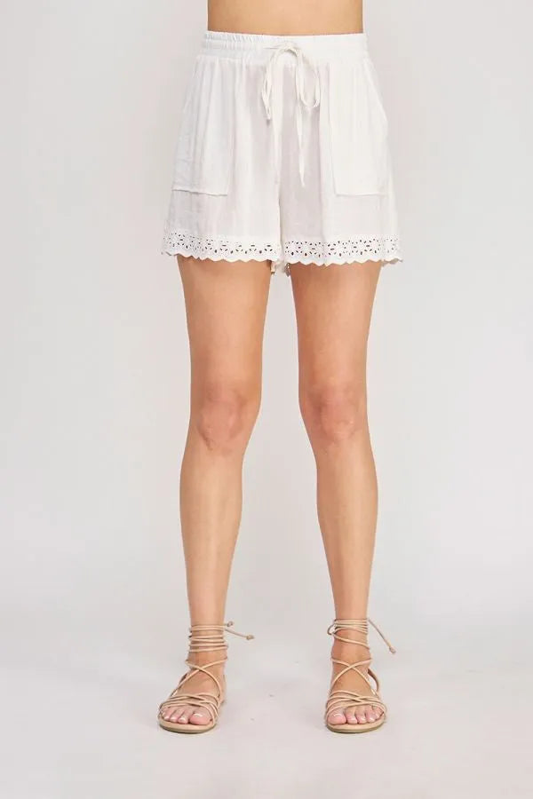 White linen blend drawstring waist shorts featuring delicate eyelet trim along the hem for a stylish finish
