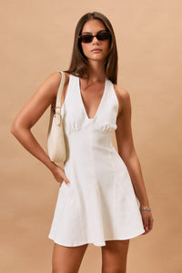 White sleeveless mini dress with deep v-neckline and flared skirt in halter neck seam denim style