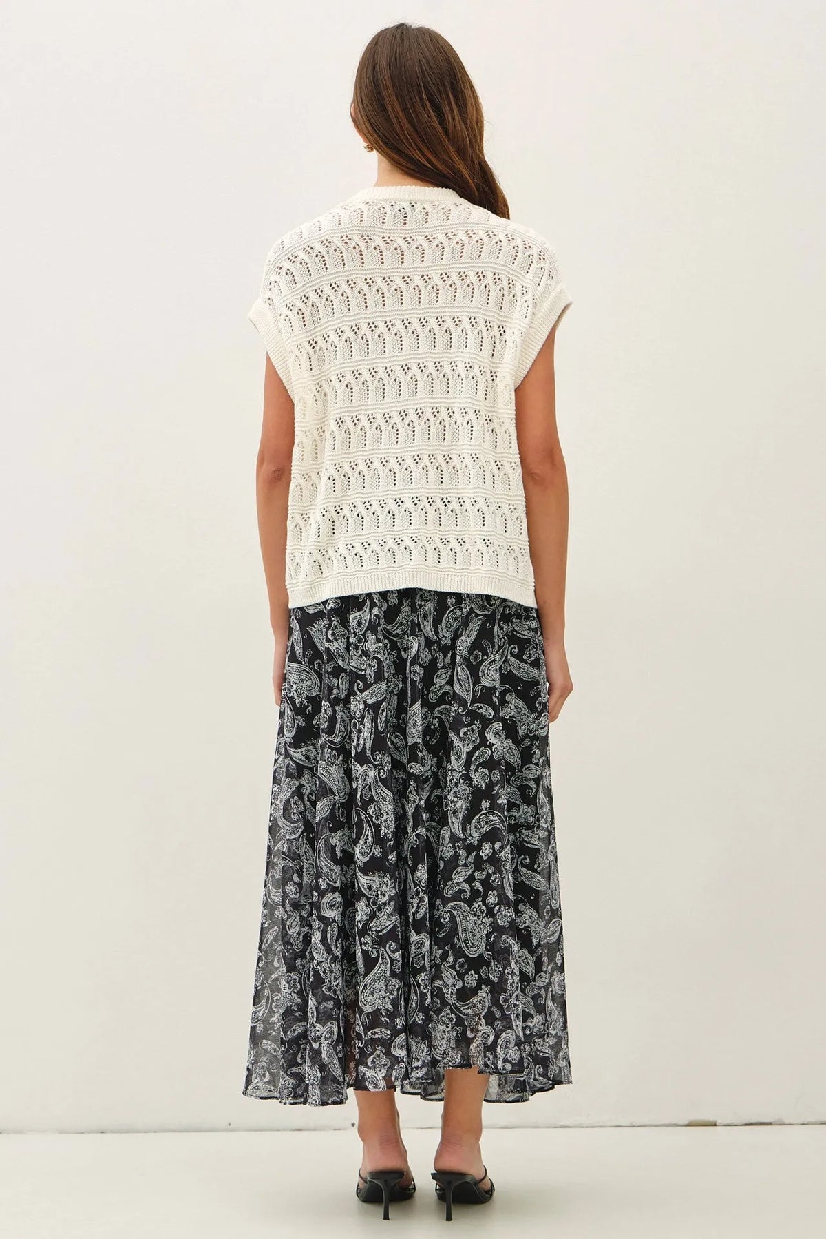 White sleeveless crochet knit boxy top with detailed lace pattern complementing knit boxy open cardigan style