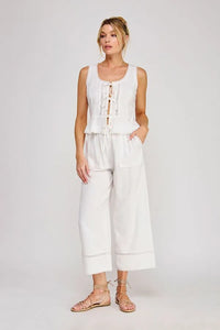 White sleeveless linen blend top with ties lace front detail and ruffled hem paired with matching wide-leg pants for women’s boho chic clothing