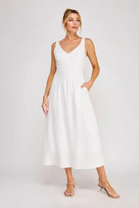 A flowing white sleeveless maxi dress with a v-neckline and pleated bodice detailing at the waist