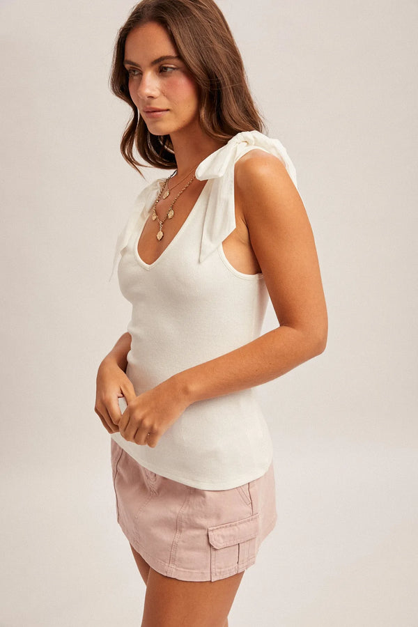 White sleeveless v neck ribbed top with bow tie detail on ruffled shoulder ties for a stylish look