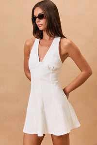 White halter neck seam denim mini dress with v-neck sleeveless design and flared skirt with gathered waist detail