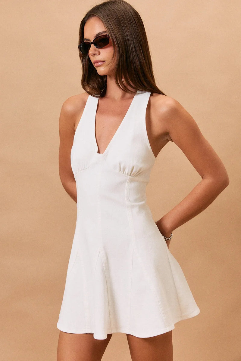 White halter neck seam denim mini dress with v-neck sleeveless design and flared skirt with gathered waist detail