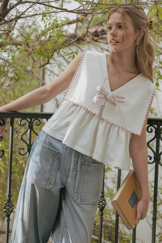 Sailor collar sleeveless top with white fabric, red-stitched edges, bow