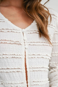 White ruched ribbon knit cardigan with textured fabric lace trim and button closures for elegant layering