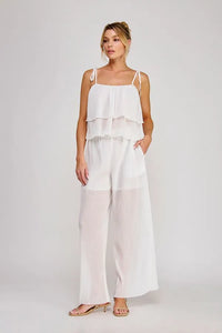 White tiered spaghetti strap jumpsuit with sheer overlay and wide-leg pants featuring textured woven tie straps