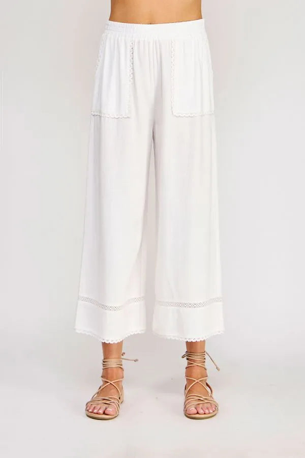 White linen blend crop pants with lace trim at hem and pockets featuring delicate wide-leg design