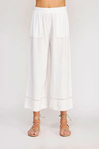 White linen blend crop pants with lace trim at hem and pockets featuring delicate wide-leg design