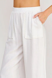 White wide-leg linen blend crop pants with delicate lace trim along side seams and pocket edges