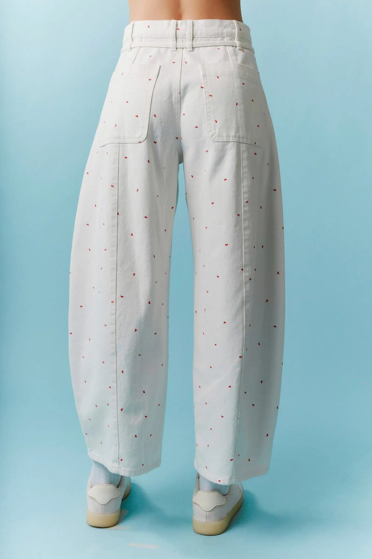High waist white wide-leg trousers with subtle red mini bow print and waist tie in barrel denim style