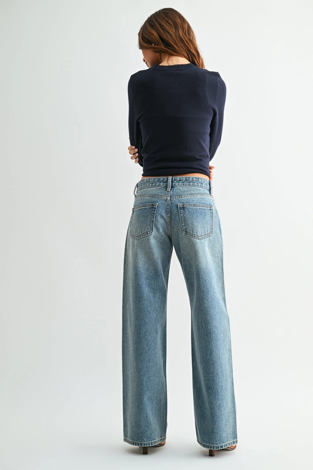 Wide-leg denim jeans in light blue wash with low rise baggy fit classic back pockets and belt loops shown from the back side