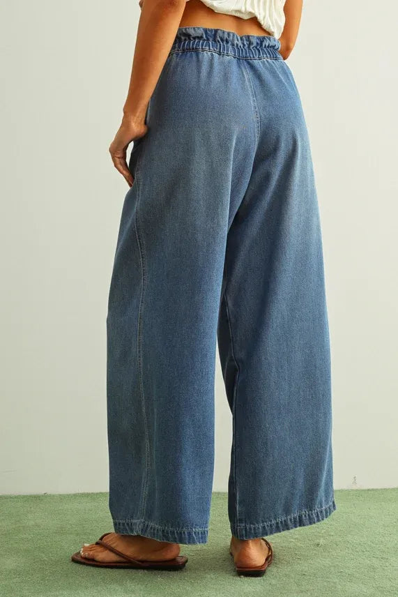 Pleated cotton belt denim pants in medium-wash blue with wide-leg cut, elastic waistband, and rolled cuffs