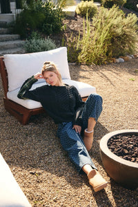 Woman wearing black knitted sweater with blue jacquard polka dot french girl jacquard polka dot barrel leg jeans