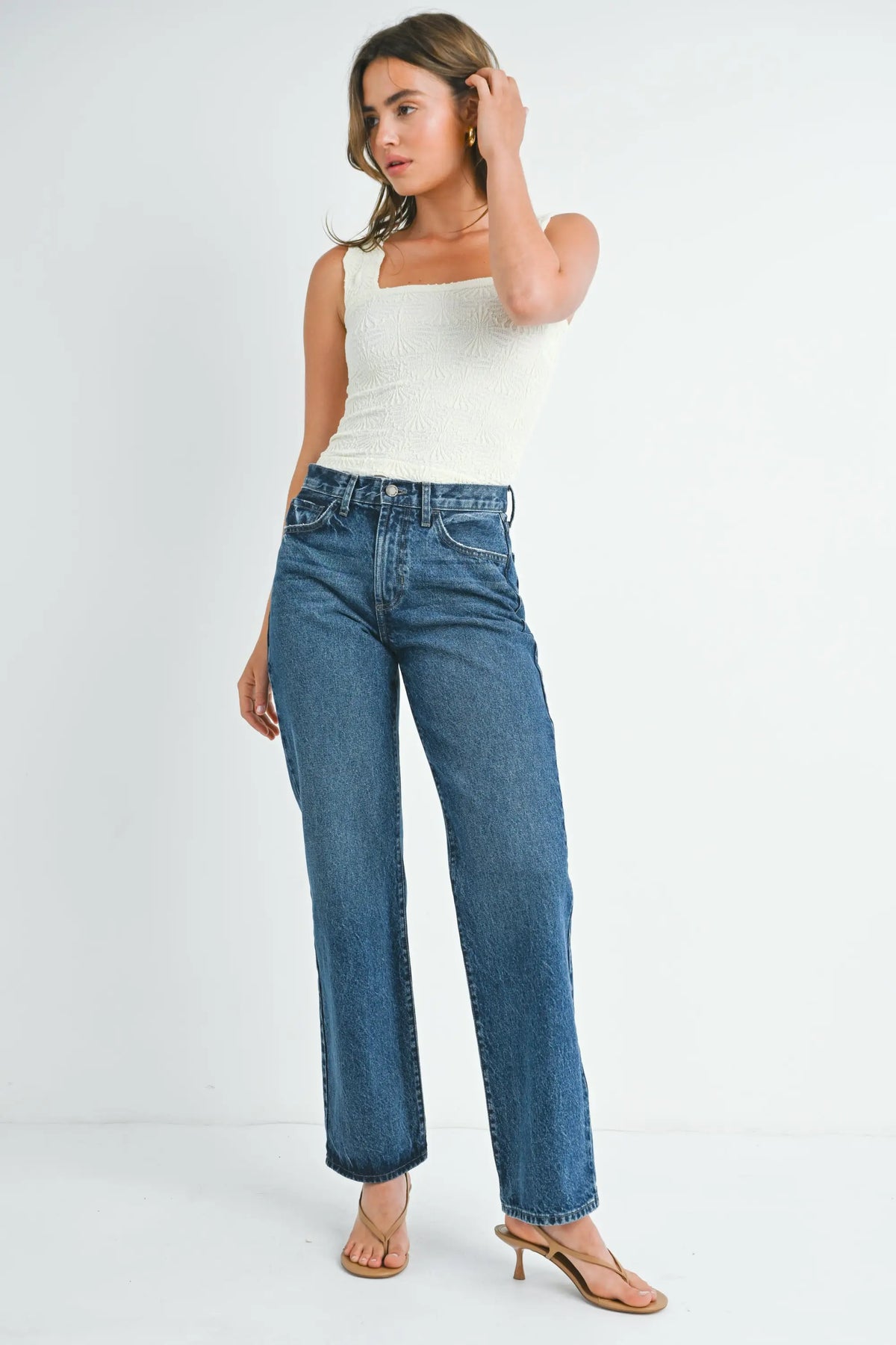 Woman wearing cream square-neck tank top and high-rise relaxed fit straight leg denim jeans