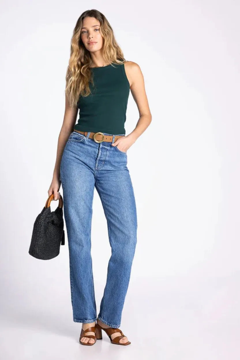 Woman wearing dark green sleeveless evie basic tank paired with blue denim jeans and a brown belt