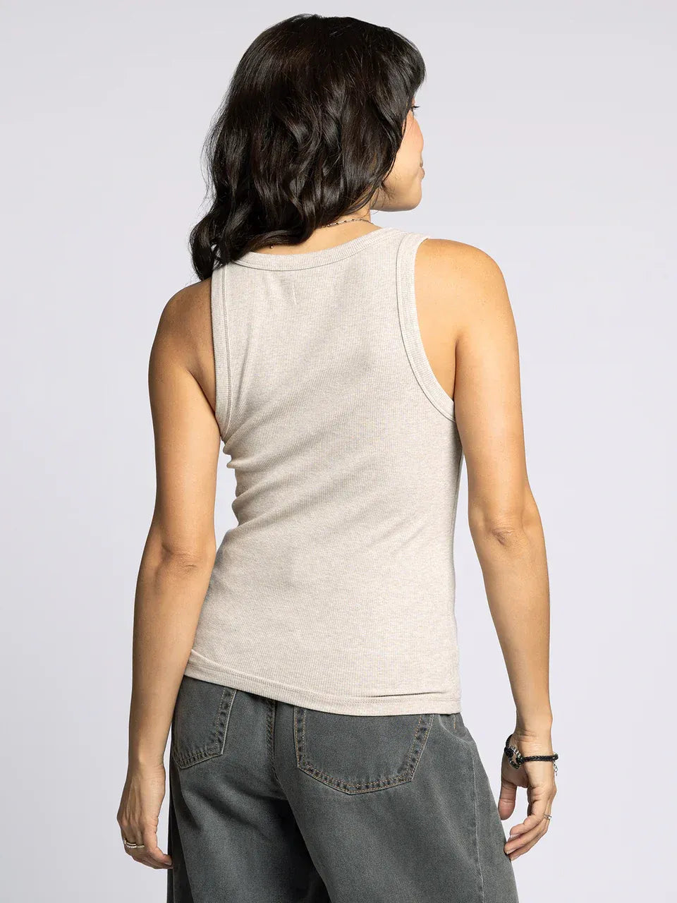 Woman modeling the Edlin Basic Tank in light beige with dark grey wide-leg pants
