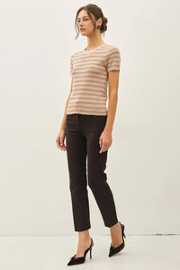 A woman wears a beige and brown scallop edge short sleeve sweater top paired with black cropped trousers