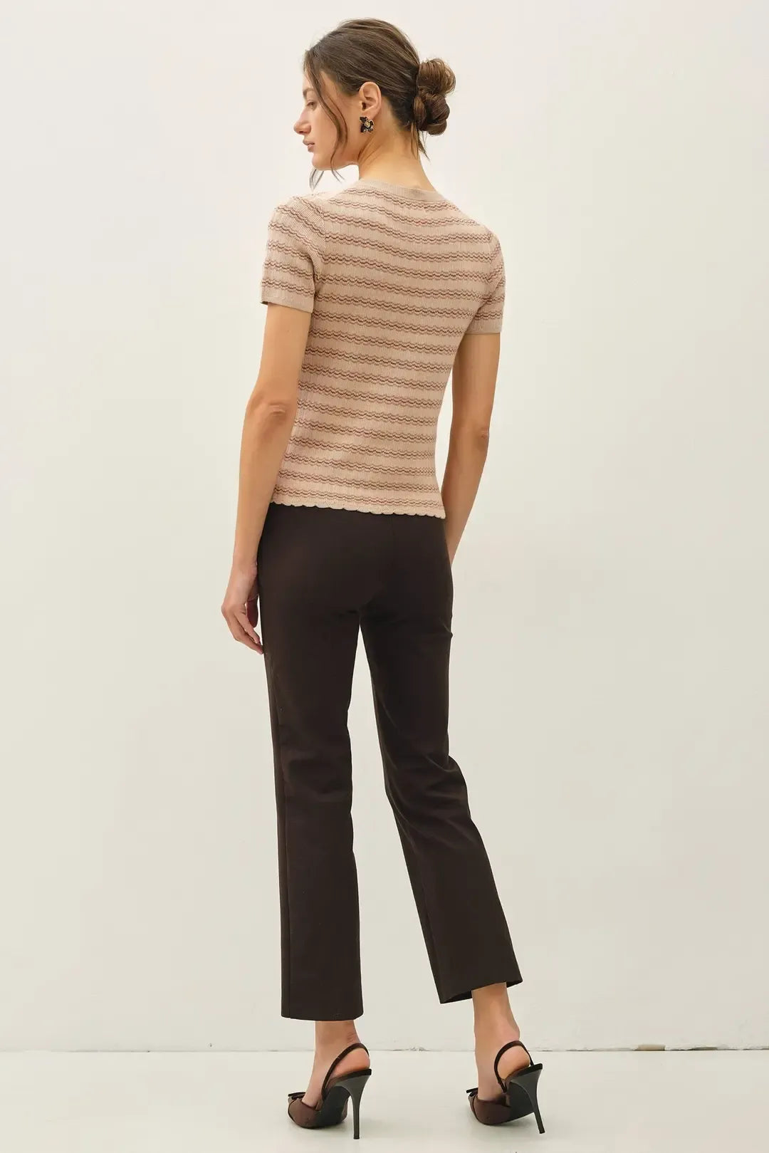 A woman wears a beige and brown striped scallop edge short sleeve knit sweater top with a scalloped hemline