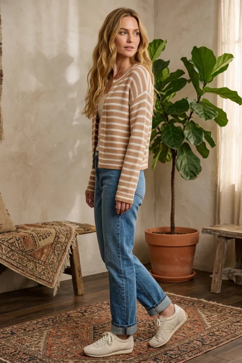 A woman wearing a beige and cream striped knit open ribbed cardigan with ribbed cuffs