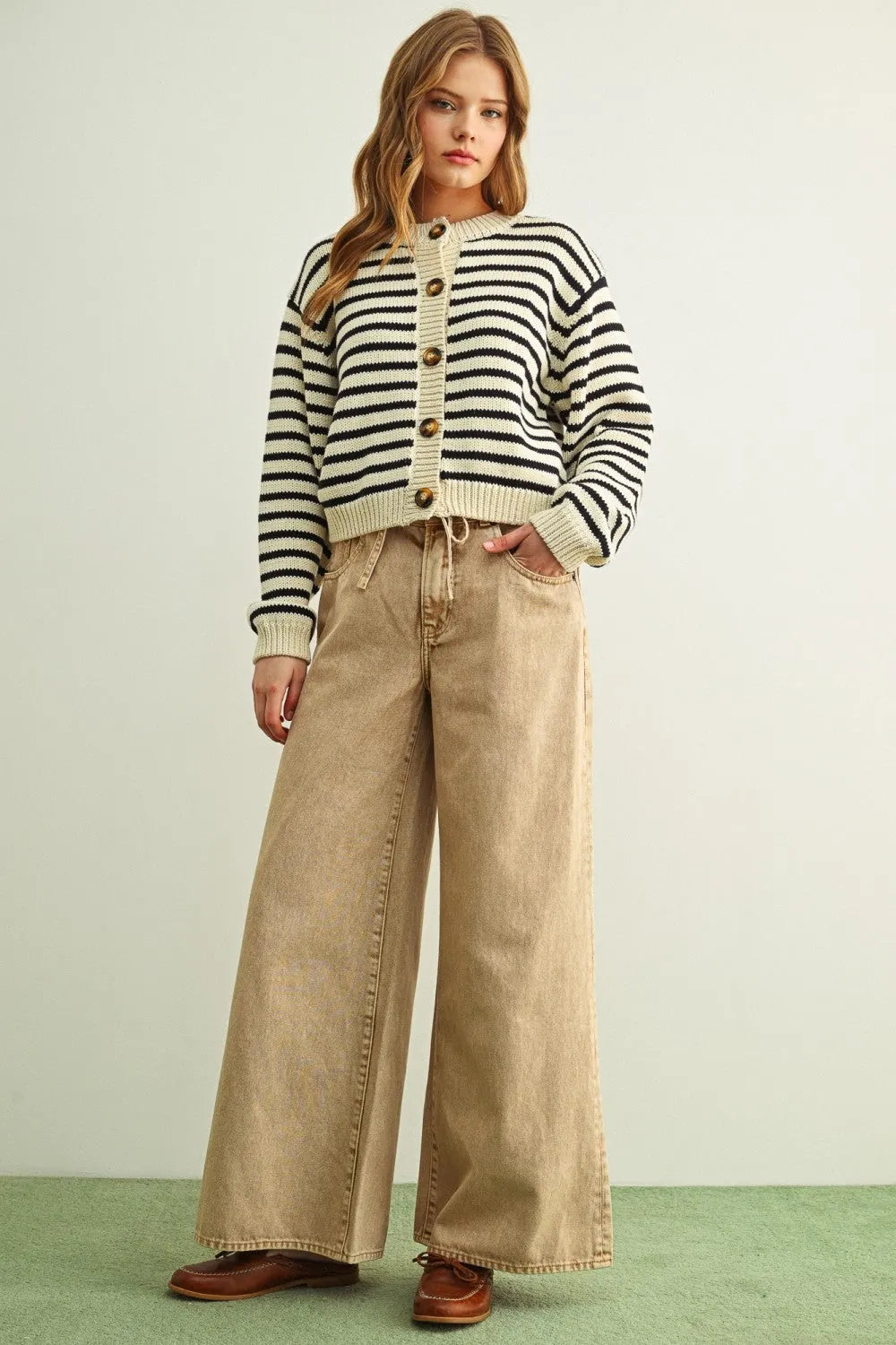 A woman wearing a black and cream striped pattern button front knitted cardigan with wooden buttons