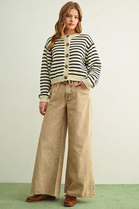 A woman wearing a black and cream striped pattern button front knitted cardigan with wooden buttons