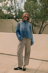 A woman wears a blue denim jacket with rolled-up sleeves styled denim jacket over leopard-print wide-leg pants